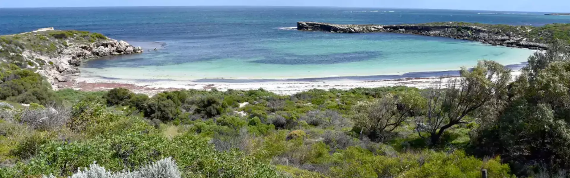 Scenic beach view with turquoise waters and greenery.