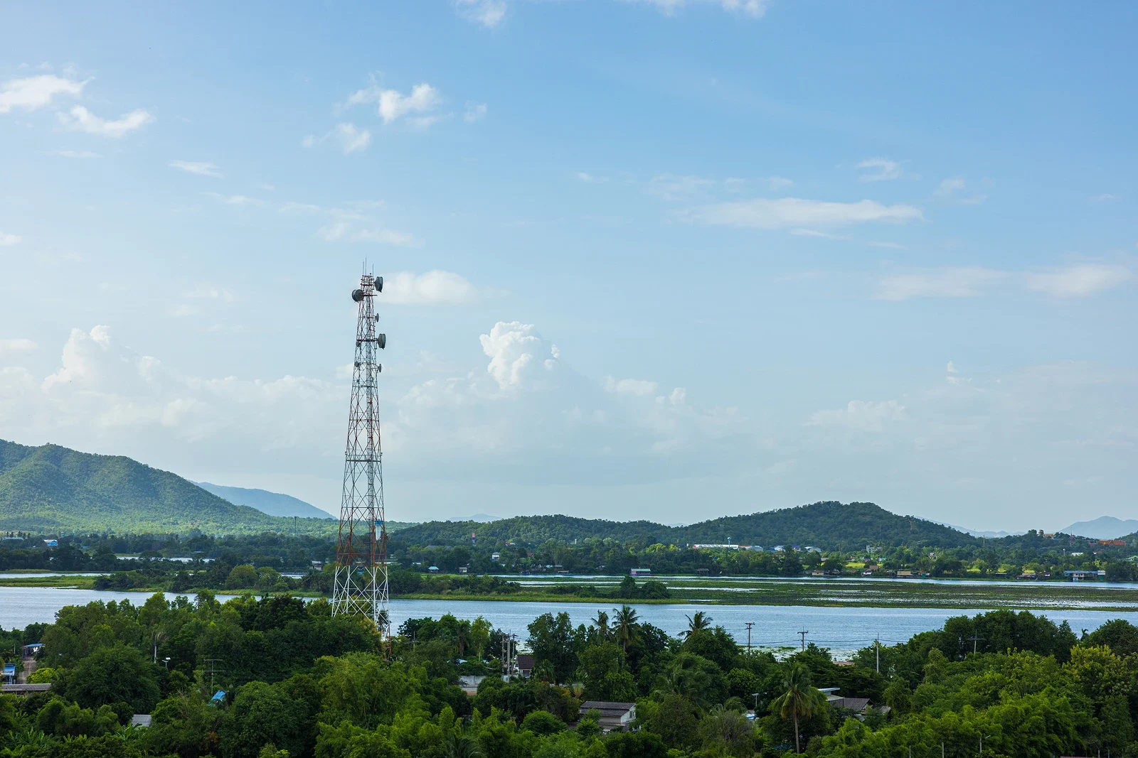 Communication tower with mountains and river backdrop.