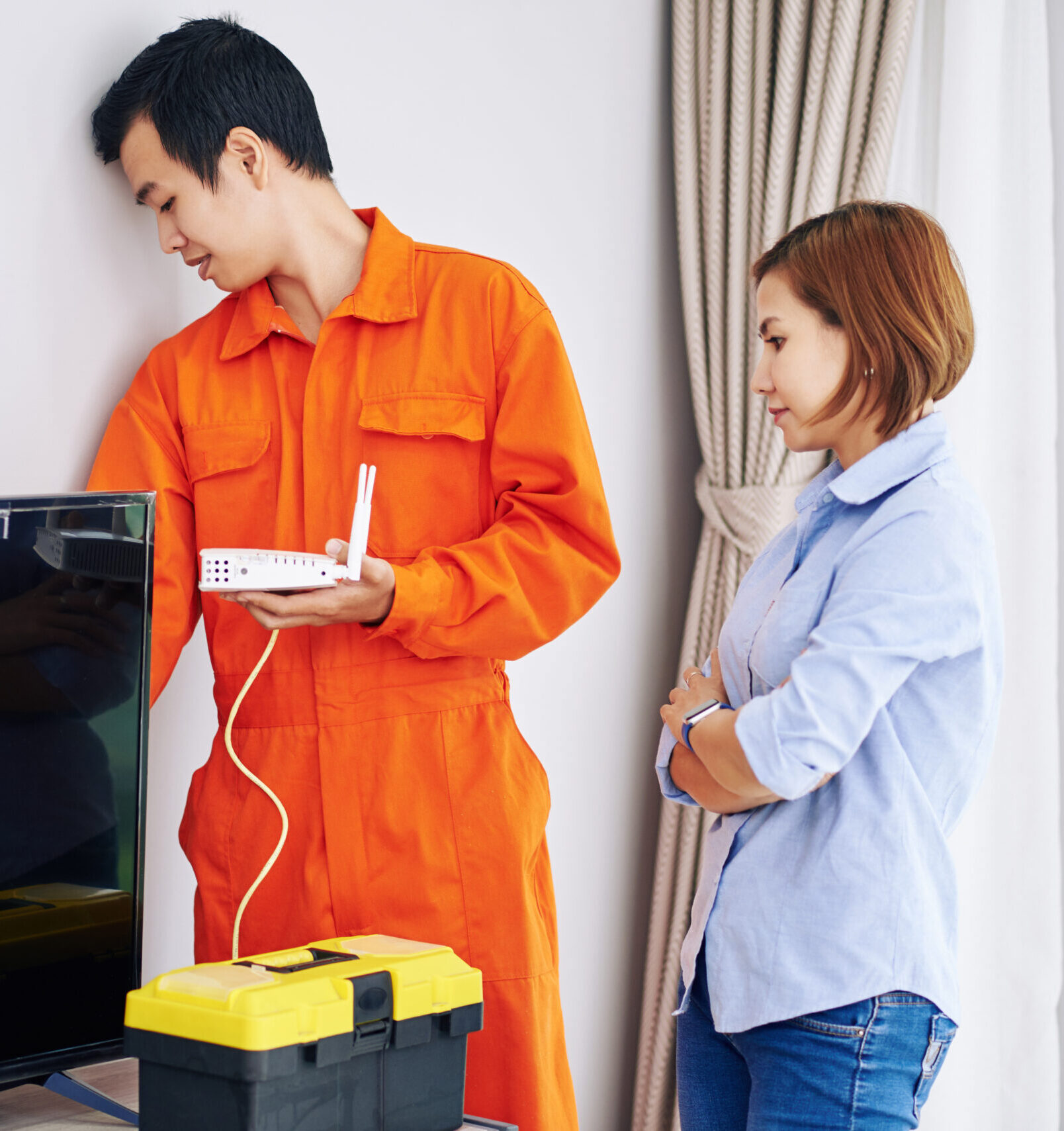Technician installing equipment while homeowner observes.
