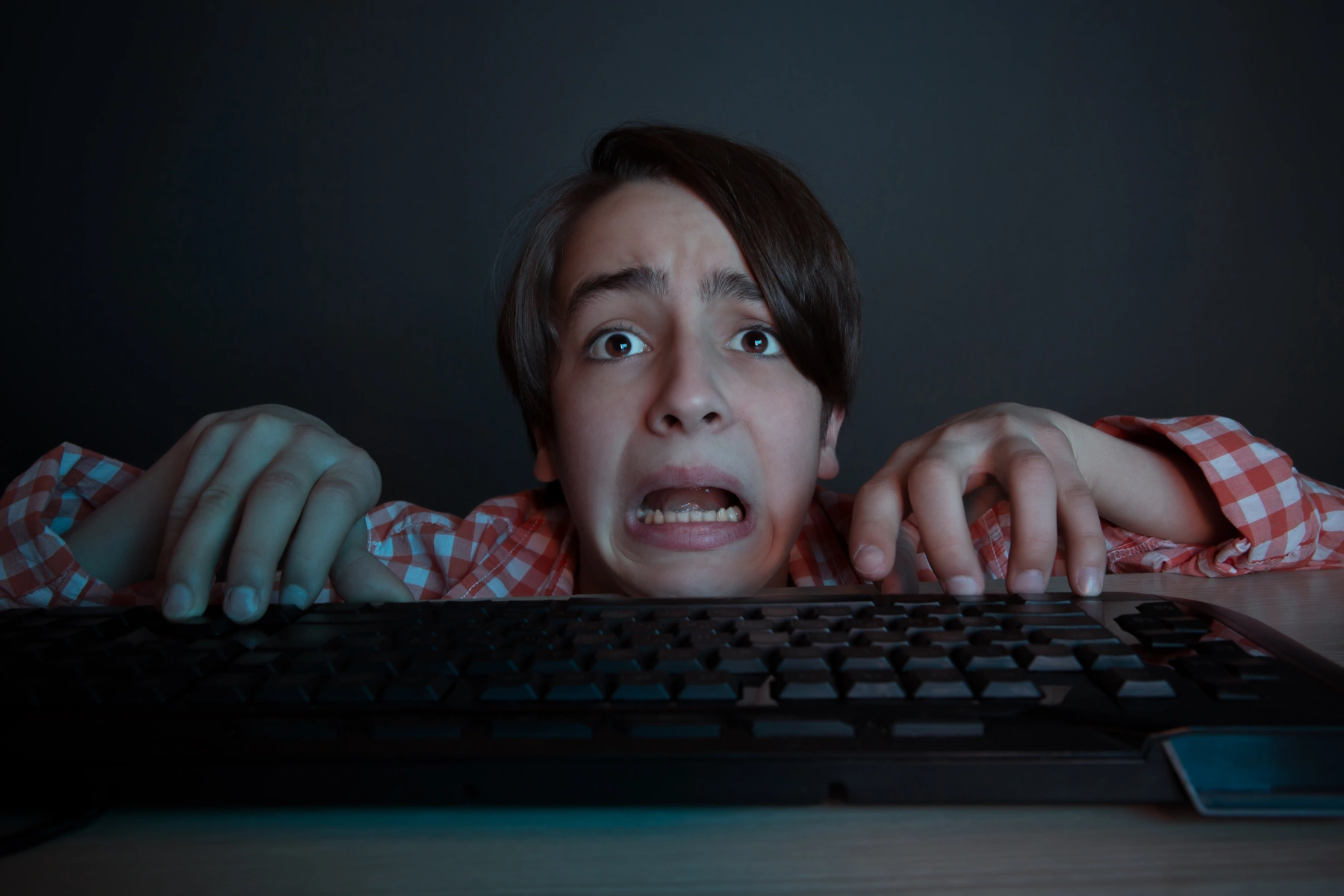 A frightened boy staring at a keyboard.