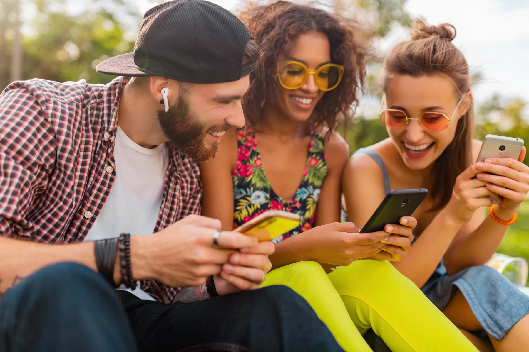 Friends enjoying time outdoors, using smartphones.